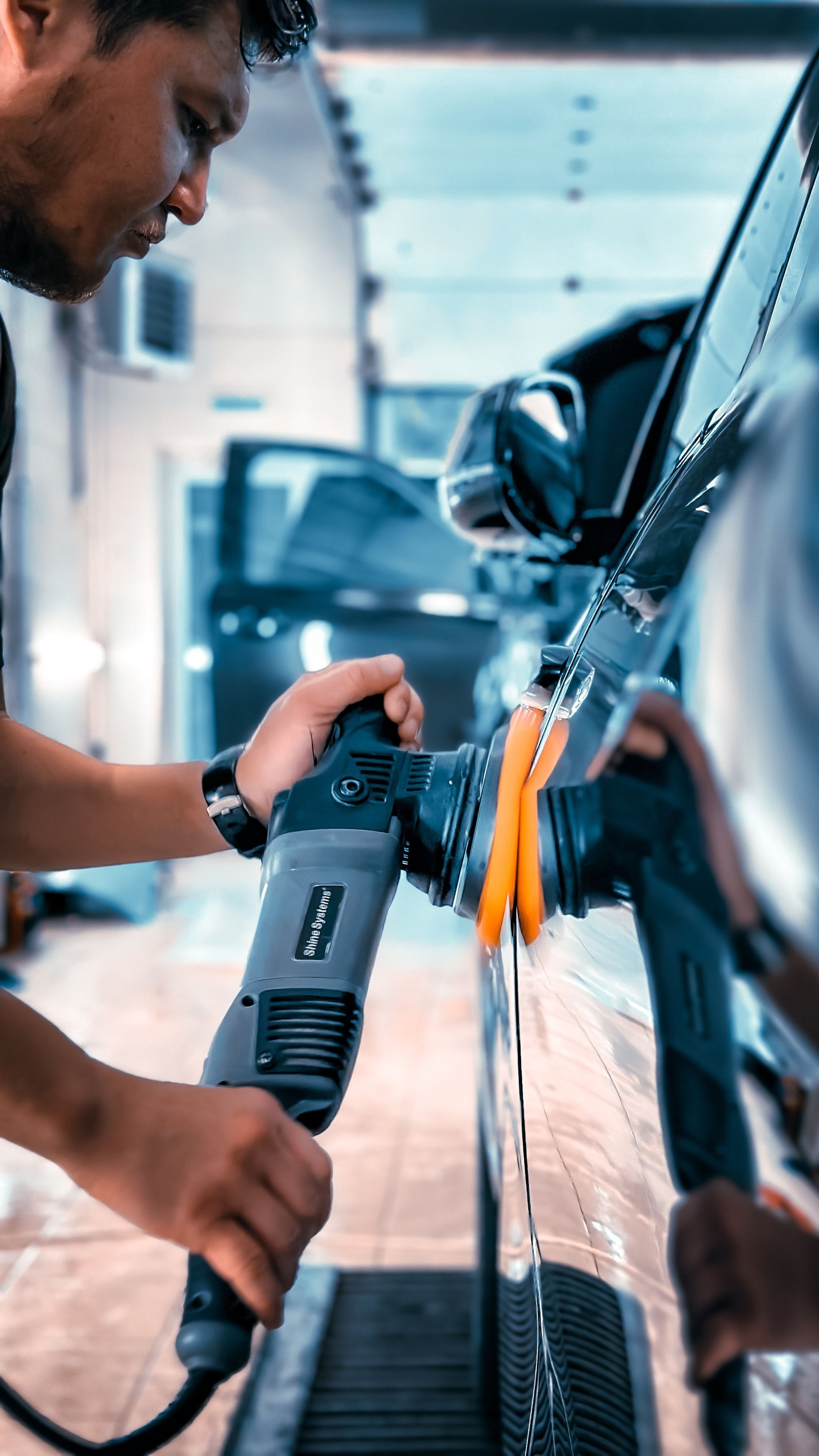 Technician polishing a car's paint with a dual-action polisher